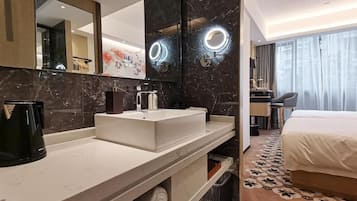 Een moderne hotelbadkamer met een grote spiegel, twee wastafels, een koffiezetapparaat en een handdoekrek.