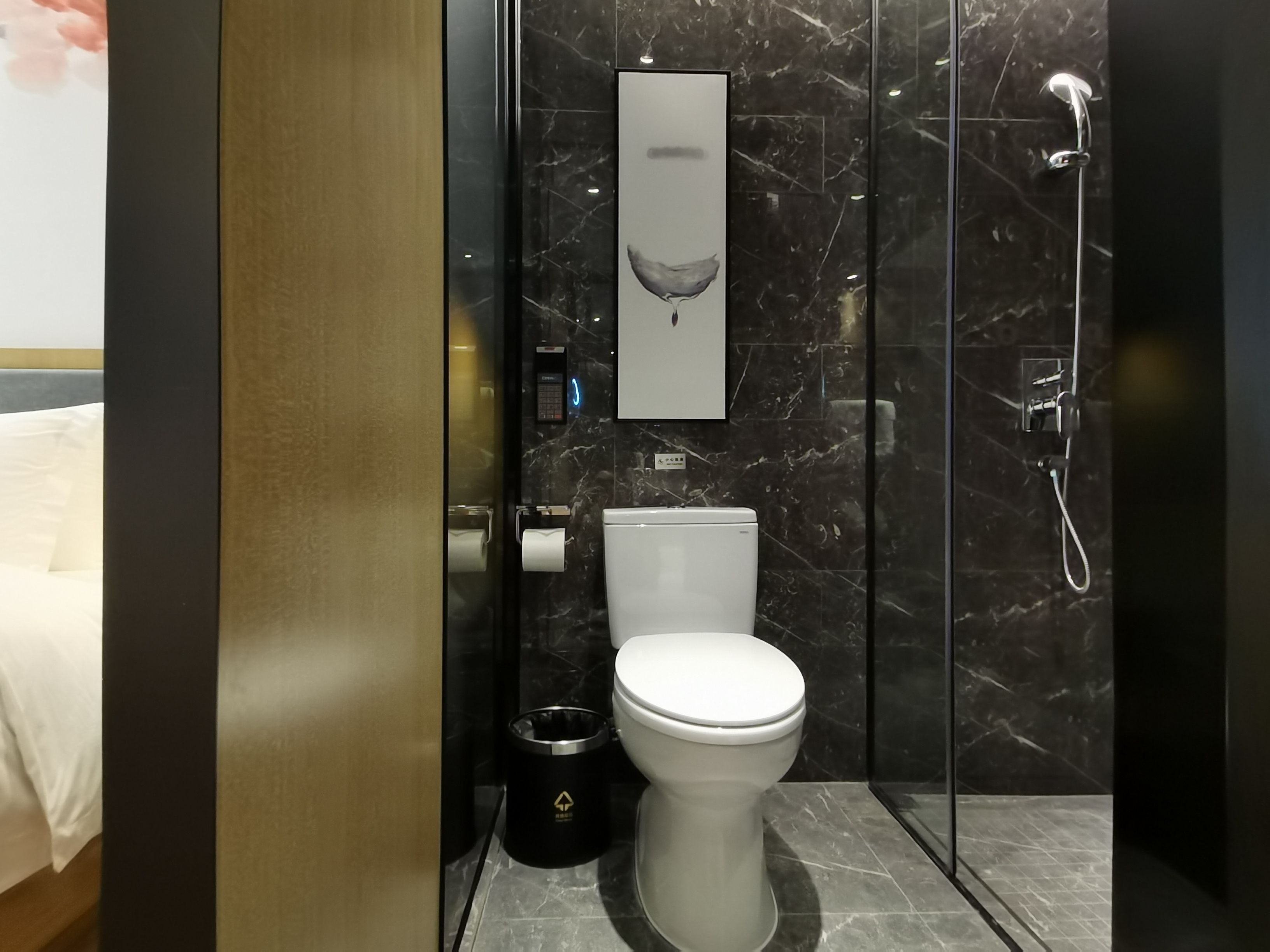 Une salle de bain moderne équipée de toilettes, d’un sèche-mains, d’une poubelle et d’une douche.