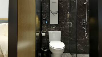 Une salle de bain moderne équipée de toilettes, d’un sèche-mains, d’une poubelle et d’une douche.