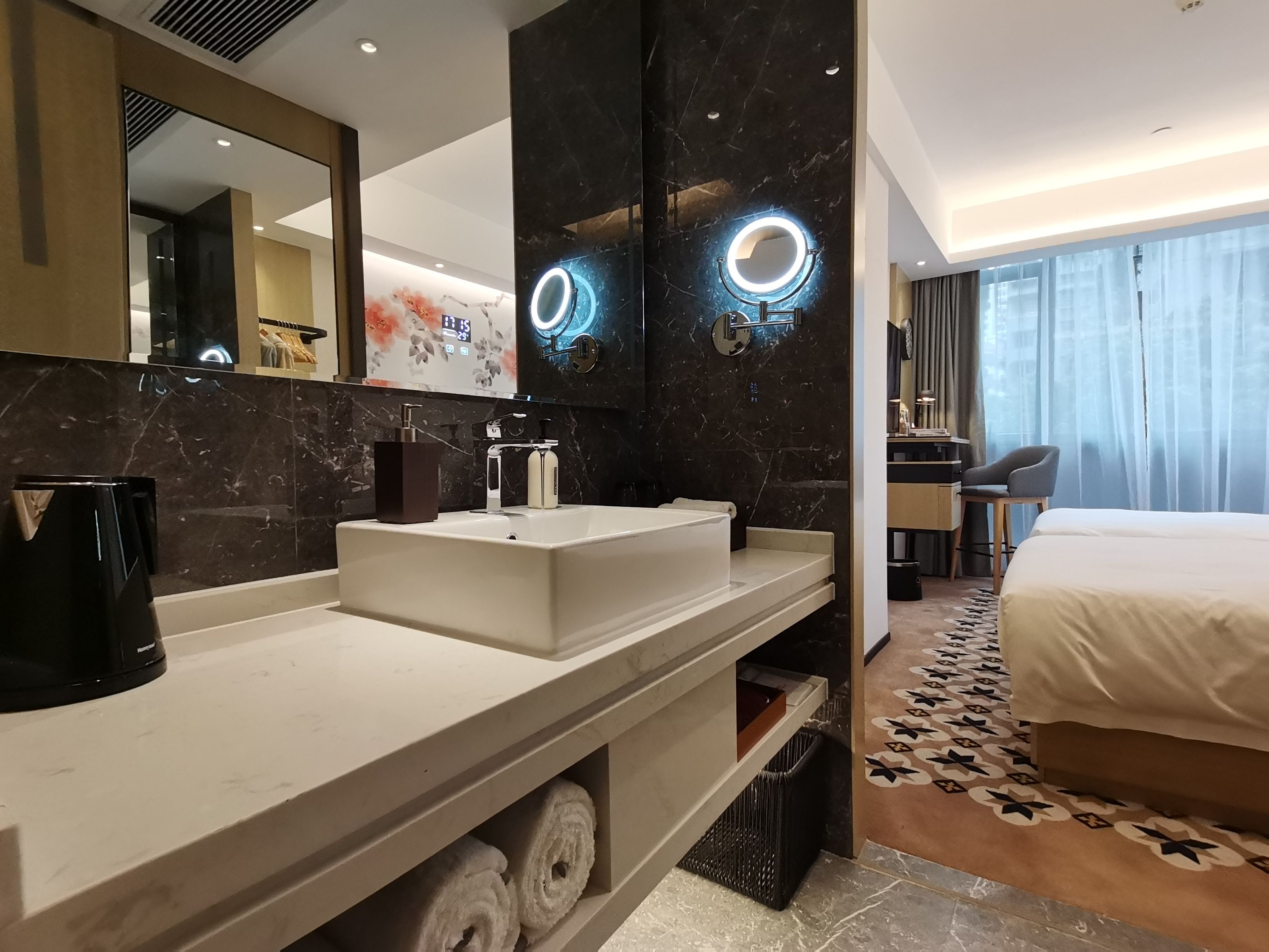 A modern hotel bathroom with a large mirror, a sink, and a toilet.