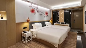 Una habitación de hotel con una cama grande, mesitas de noche, una obra de arte colgada en la pared y un armario.