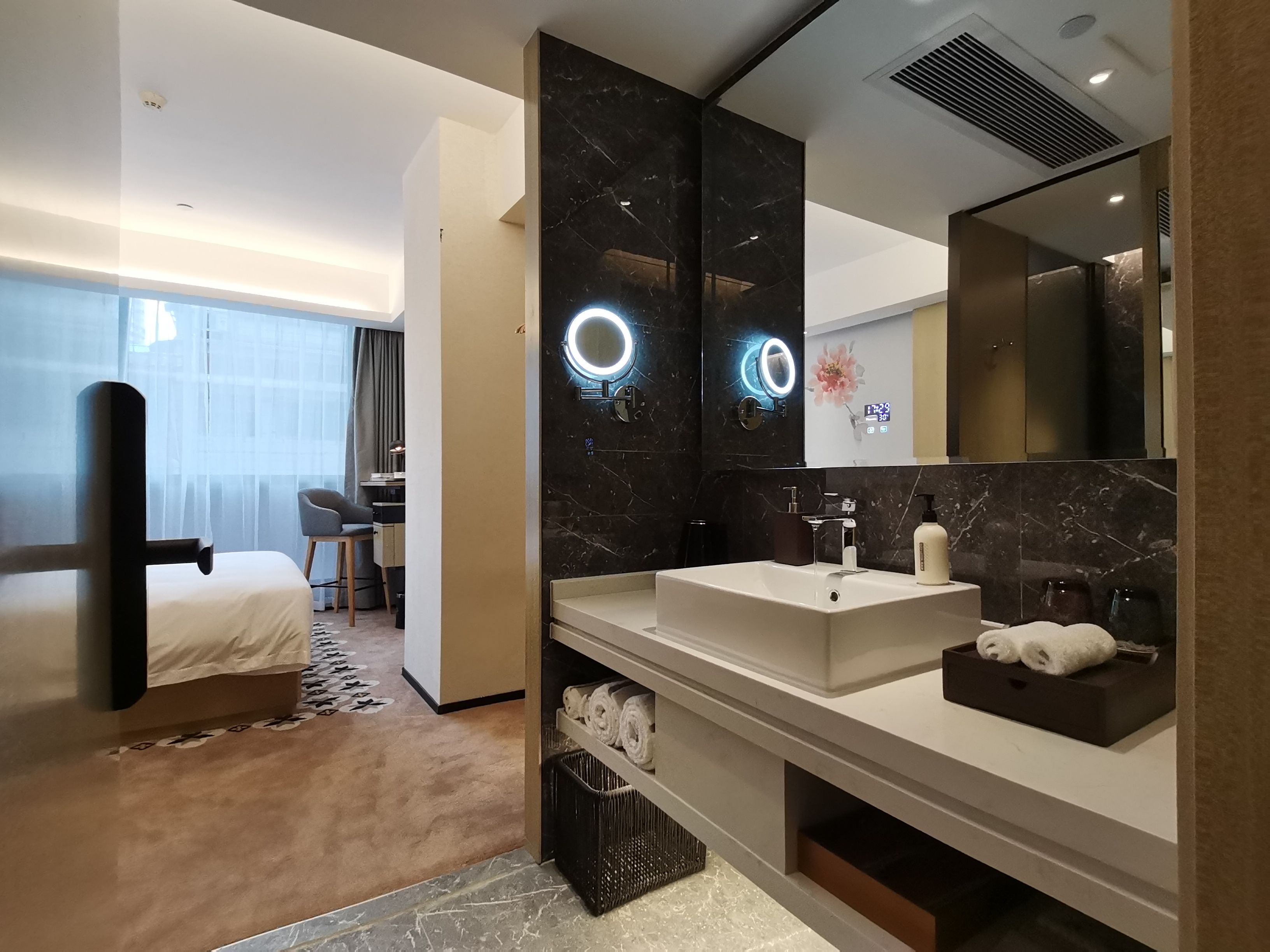 Een moderne hotelbadkamer met een grote spiegel, twee wasbakken en een opbergmeubel.