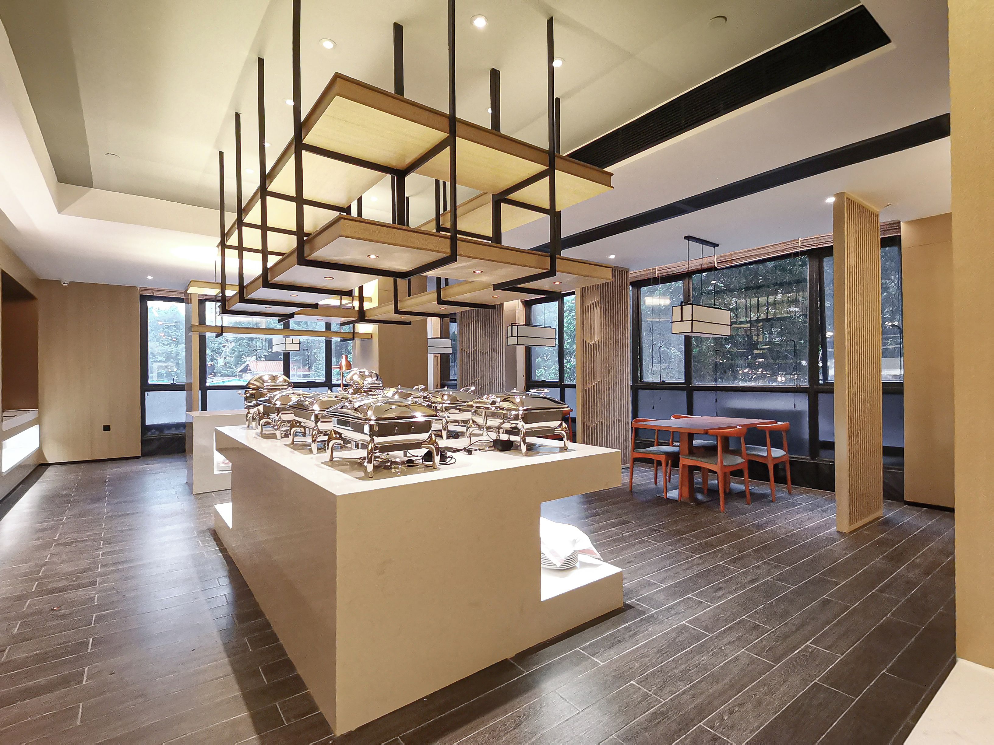 A modern interior with a central display of silver appliances, wooden flooring, and a dining area with a table and chairs.