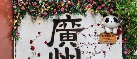 A wall with Chinese characters and a panda sticker, surrounded by greenery.