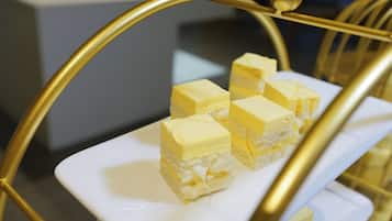 En vit, rektangulär tallrik med flera kvadratiska bitar av gul dessert, placerade på ett gyllene fat.