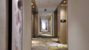 A hotel corridor with a floral carpet, wooden walls, and a sign indicating room number 246.