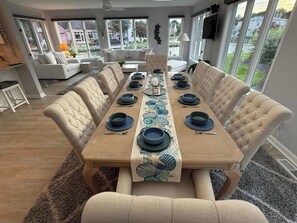 A dining area with a long table set for six, surrounded by cushioned chairs. - The Cove at Ocean Pines | Boater’s Paradise (Ocean Pines)
