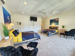 A bedroom with two beds, a ceiling fan, a TV, and artwork on the walls. - The Cove at Ocean Pines | Boater’s Paradise (Ocean Pines)