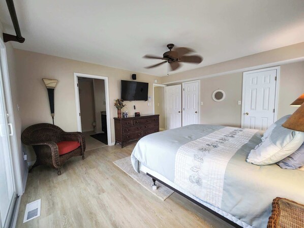 Quarto com cama, ventoinha no teto, televisão, cômoda e uma cadeira.