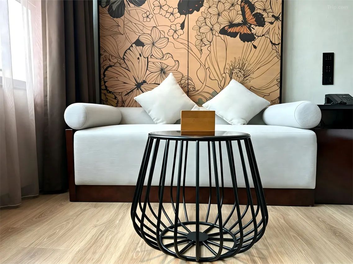 A modern room with a sofa, a round black metal table, and a floral wallpaper.