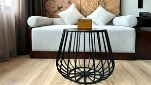 A modern room with a sofa, a round black metal table, and a floral wallpaper.