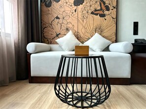 A modern room with a sofa, a round black metal table, and a floral wallpaper.