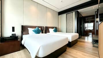 A modern hotel room with two beds, a wooden floor, a nightstand, and a decorative wall panel.