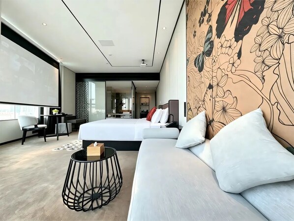 A modern hotel room with a large bed, a sofa, a small round table, and a decorative wall.