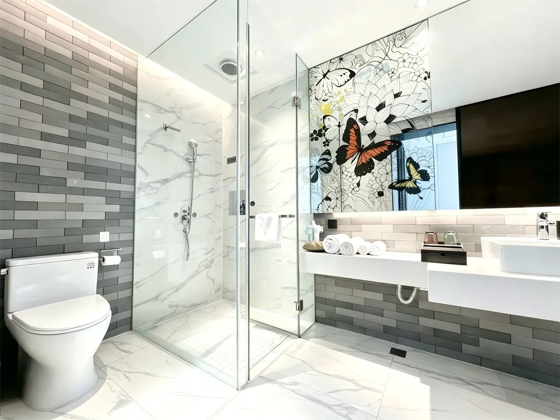A modern bathroom with a glass shower enclosure, a toilet, and a vanity with a mirror.