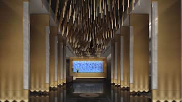 A modern lobby with a reflective floor, vertical light fixtures, and a central digital display.