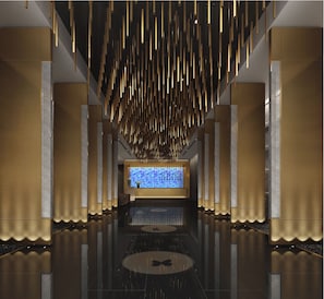 Un lobby moderno con piso reflectante, luminarias verticales y una pantalla digital central.