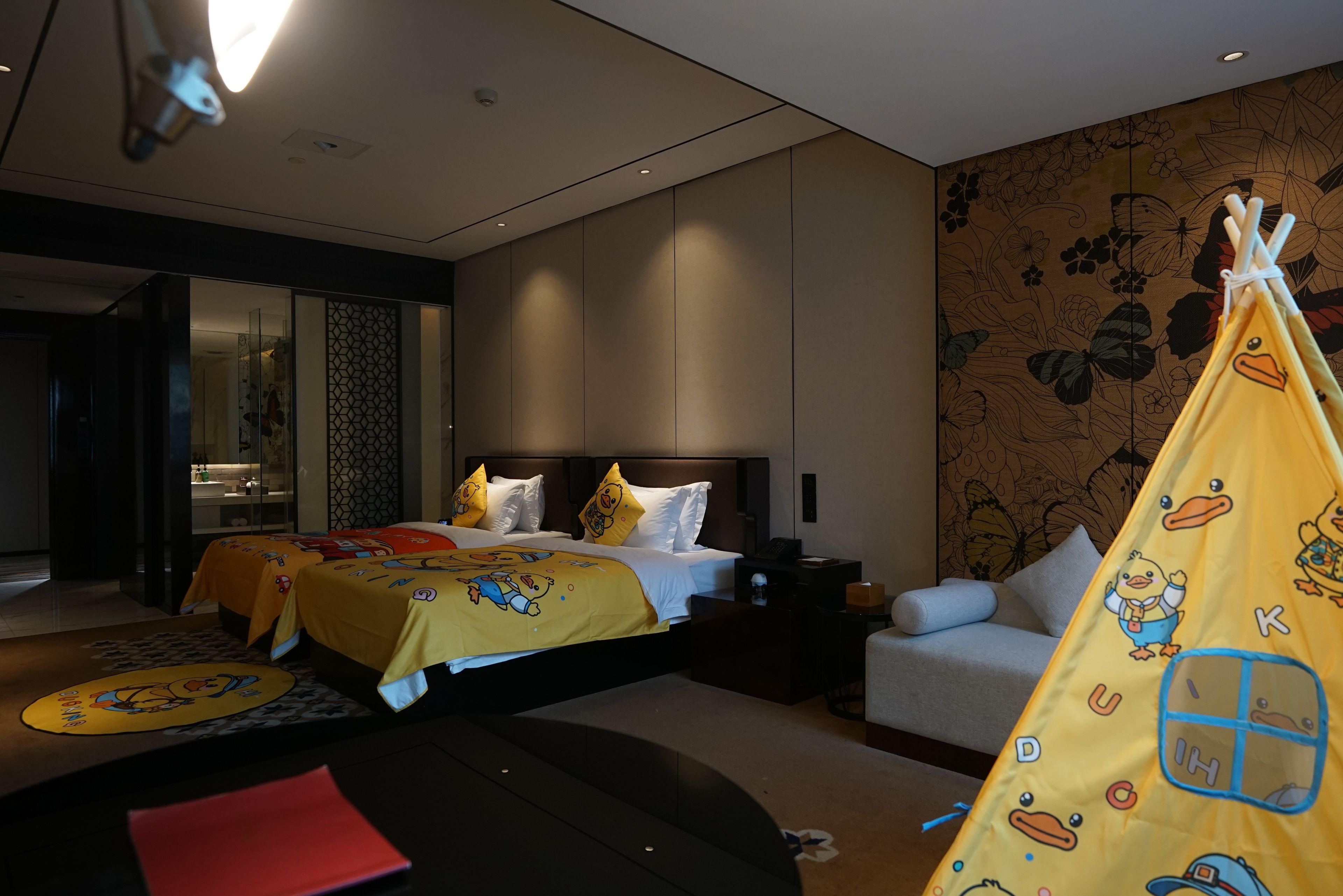 Een hotelkamer met een bed, een sofa, een nachtkastje en decoratieve wandbekleding.