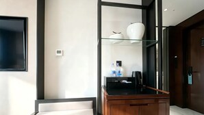 A modern bathroom with a glass shower enclosure, a wooden vanity, and a mounted toilet.