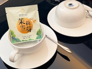 A white teacup and saucer with a tea bag labeled 'Jasmine Tea' and a white teapot with a lid. - Paco Hotel Shuyin Road Guangzhou (Guangzhou)