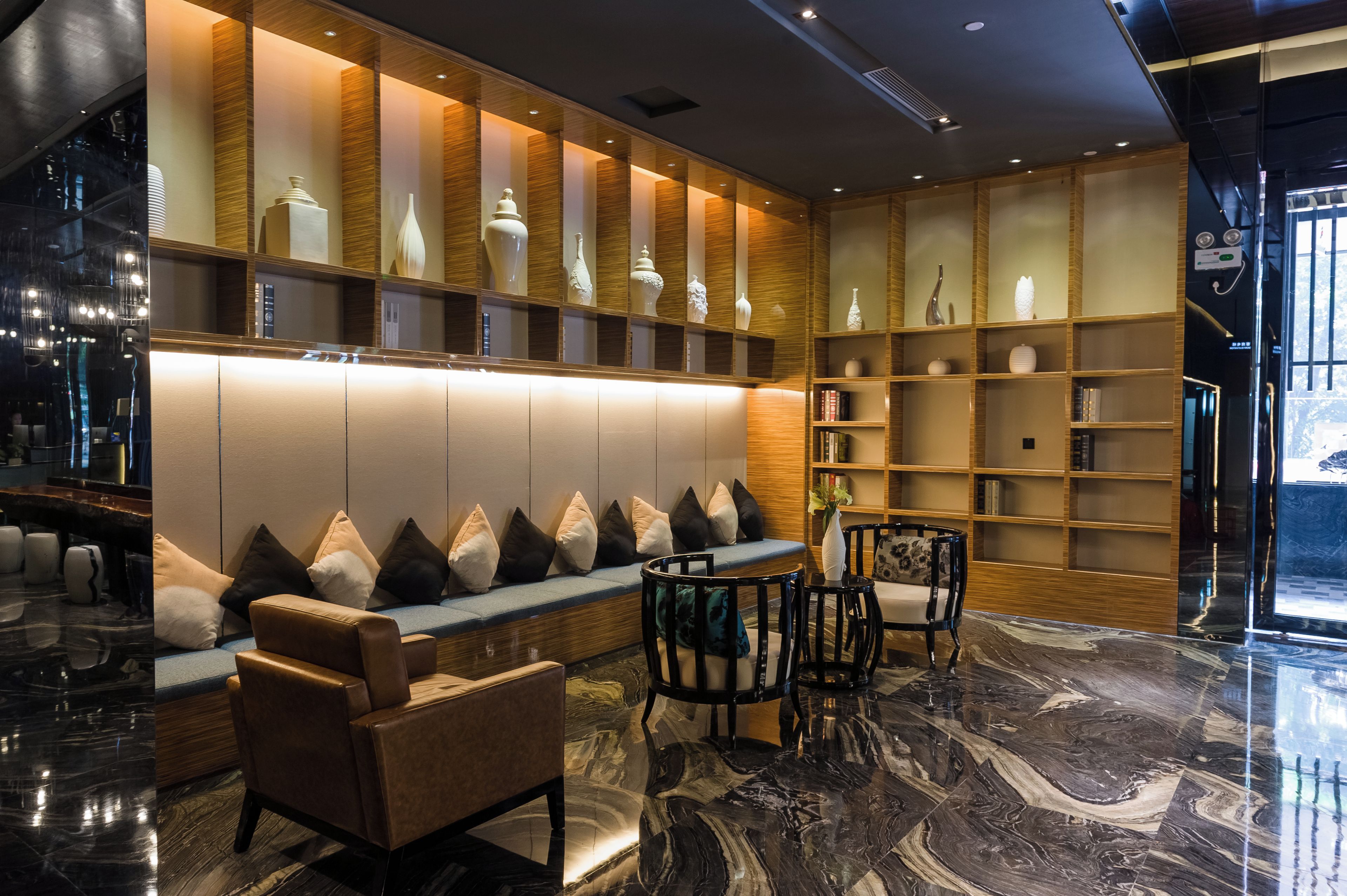 A modern lobby with a seating area, bookshelves, and a marble floor.
