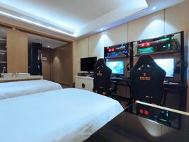 Una camera d'albergo con due letti, una scrivania con computer e una televisione.