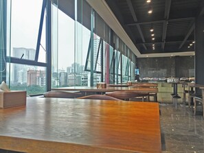 A spacious indoor area with large windows, a long wooden table, and multiple seating arrangements. - Paco Hotel Shuyin Road Guangzhou (Guangzhou)