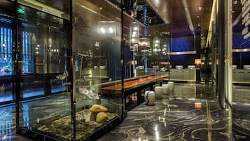 Eine moderne Lobby mit Glastrennwand, einer Rezeption und einer Sitzecke mit Marmorboden.