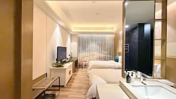 A hotel room with a bed, a desk, a mirror, and a bathroom with a sink and toilet.