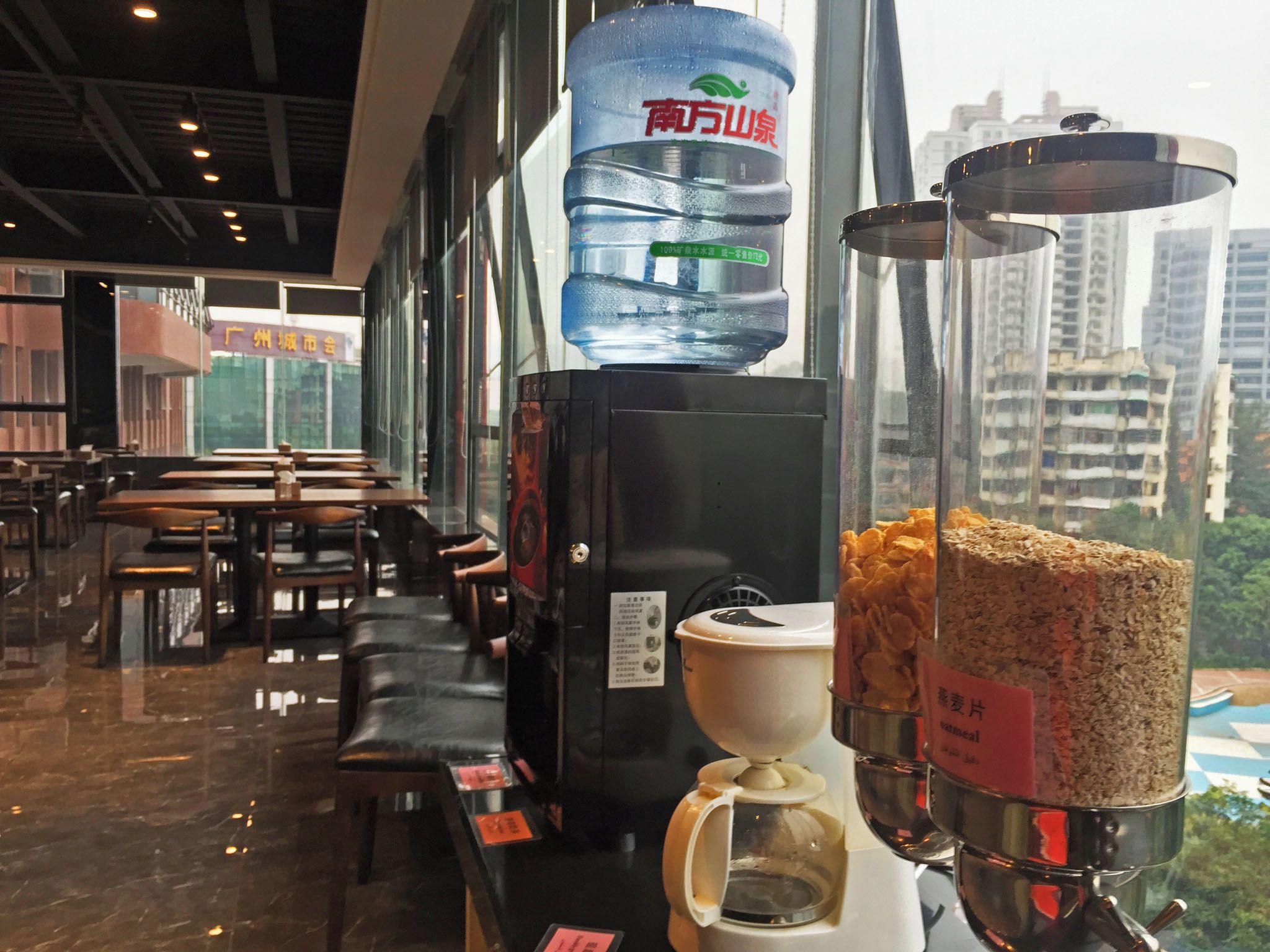 A café interior with seating, a water dispenser, and a coffee machine.