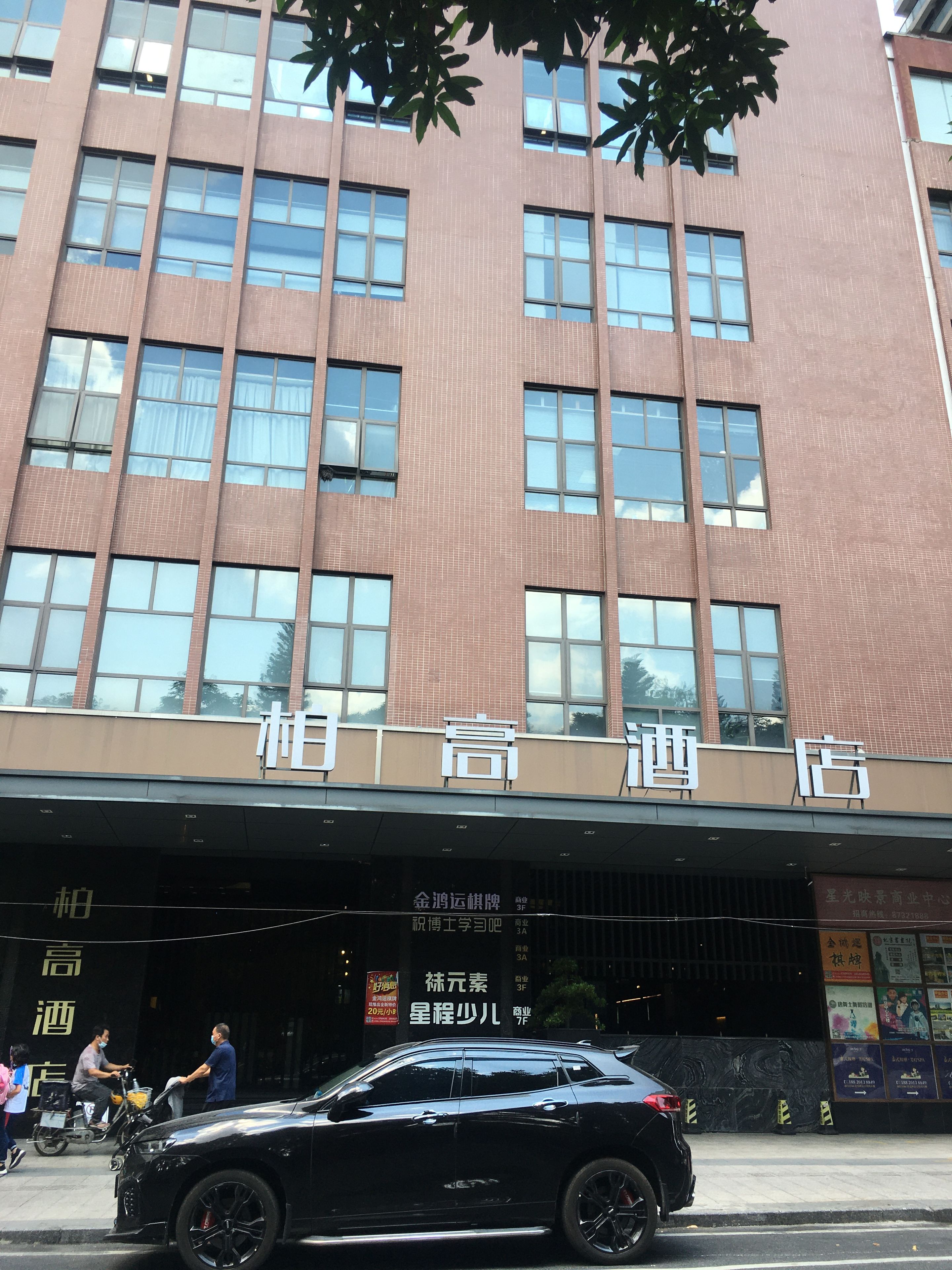 A hotel with a modern facade, multiple windows, and a signboard with text.