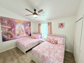 A bedroom with two beds, a ceiling fan, a large wall mural, and a window with curtains. - Disney Family Home/3-bedroom townhome with private pool in Kissimmee. (Kissimmee)