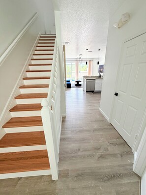 A staircase with wooden steps leading to a kitchen area with a dishwasher and a dining table. - Disney Family Home/3-bedroom townhome with private pool in Kissimmee. (Kissimmee)