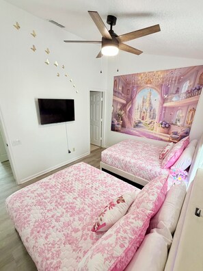 Ein Schlafzimmer mit zwei Betten, einem Deckenventilator, einem Flachbildfernseher und einem Wandbild.