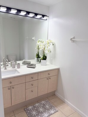 A bathroom with a white sink, mirror, and a potted orchid. - Disney Family Home/3-bedroom townhome with private pool in Kissimmee. (Kissimmee)