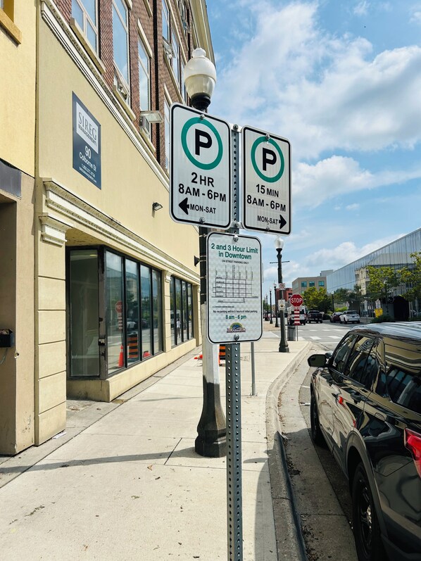 A parking sign with 2-hour parking limits and a 15-minute parking limit, next to a building with a sign for Sireg Management.