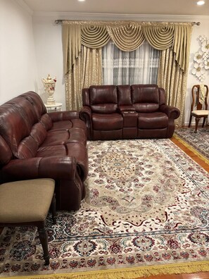 A living room with a brown leather sofa, a matching armchair, and a patterned rug. - Private Bedroom with Shared Bathroom in a single house peaceful neighborhood (Fort Washington)