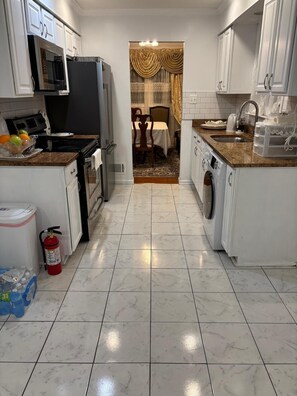 A kitchen with white cabinets, a microwave, a stove, and a washing machine. - Private Bedroom with Shared Bathroom in a single house peaceful neighborhood (Fort Washington)
