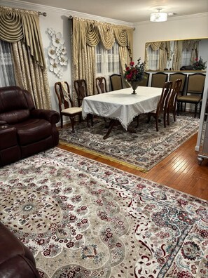 A dining area with a table set for six, surrounded by six chairs, a brown leather sofa, and a patterned rug. - Private Bedroom with Shared Bathroom in a single house peaceful neighborhood (Fort Washington)