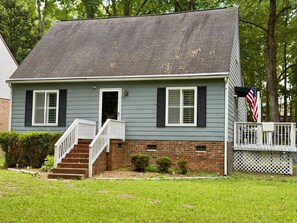 A two-story house with a front porch, a brick foundation, and a small front yard. - Duke Medical District Stay House FenceYard (Durham)