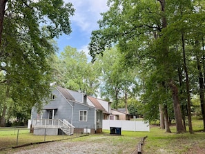 A residential property with a two-story house, a fenced yard, and mature trees.
