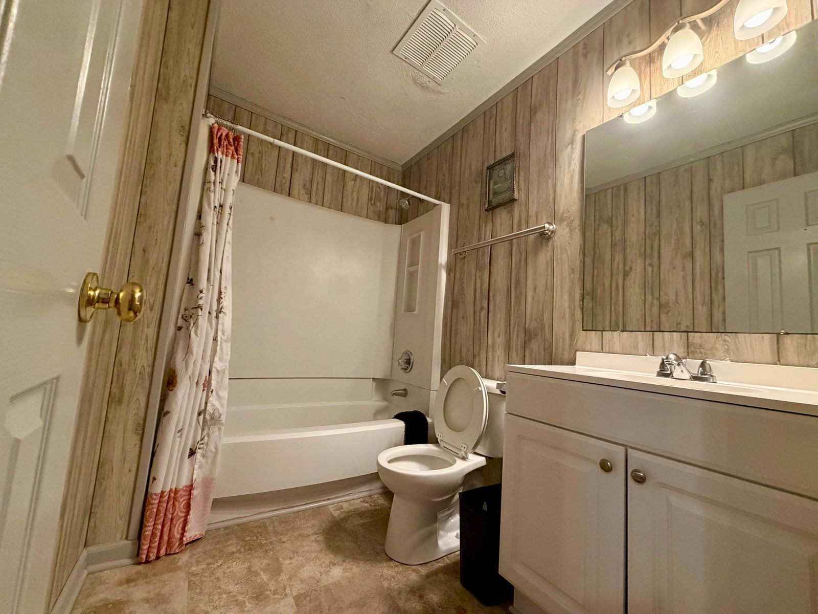 A bathroom with a bathtub, toilet, and vanity with a mirror.