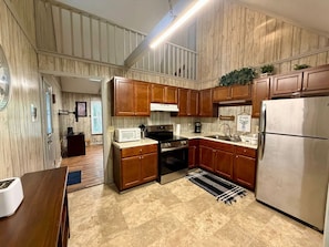 A kitchen with wooden cabinets, a stainless steel refrigerator, and a microwave.