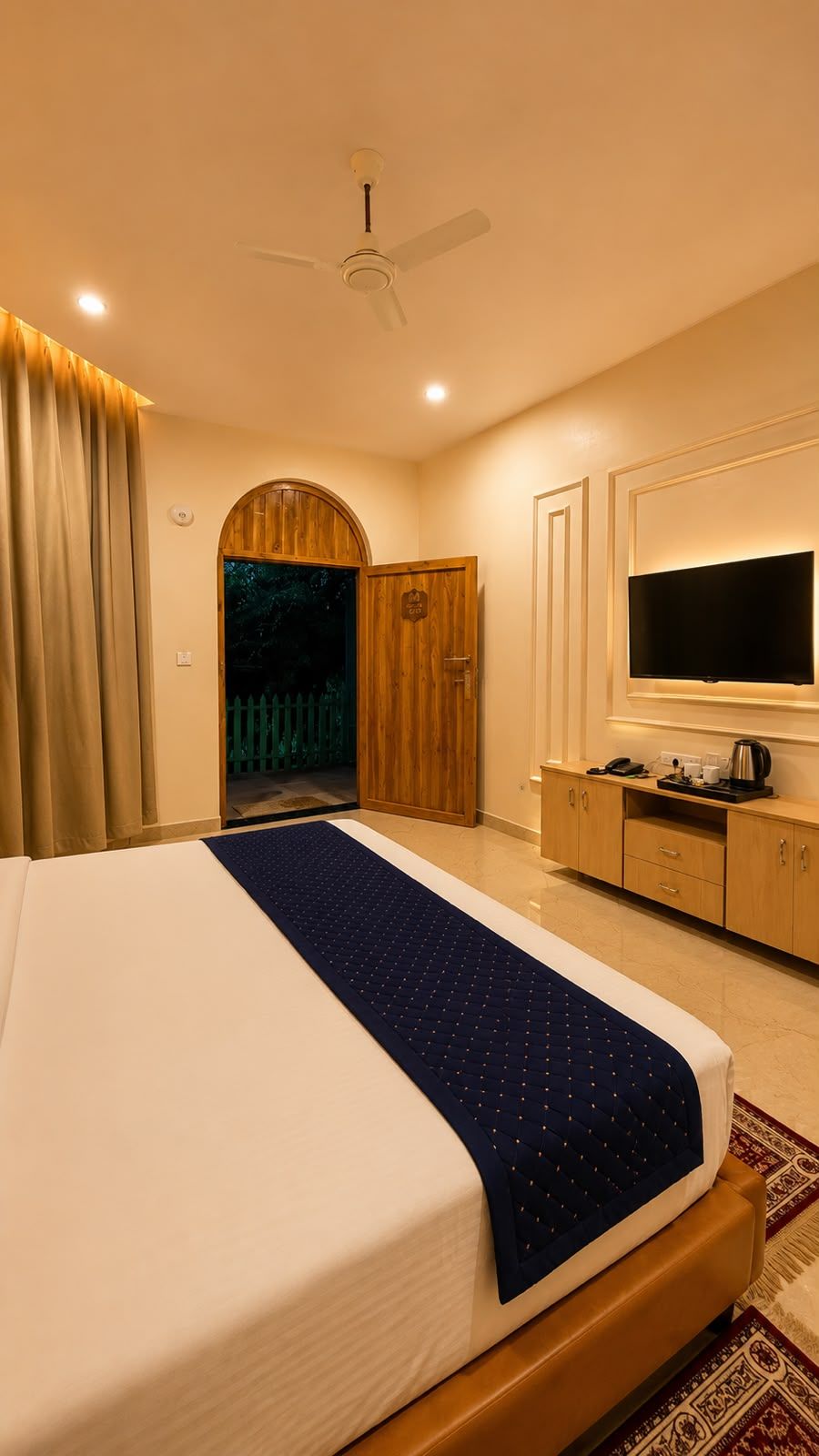 Une chambre d’hôtel comprenant un lit, une télévision, un bureau et une porte donnant sur un balcon.