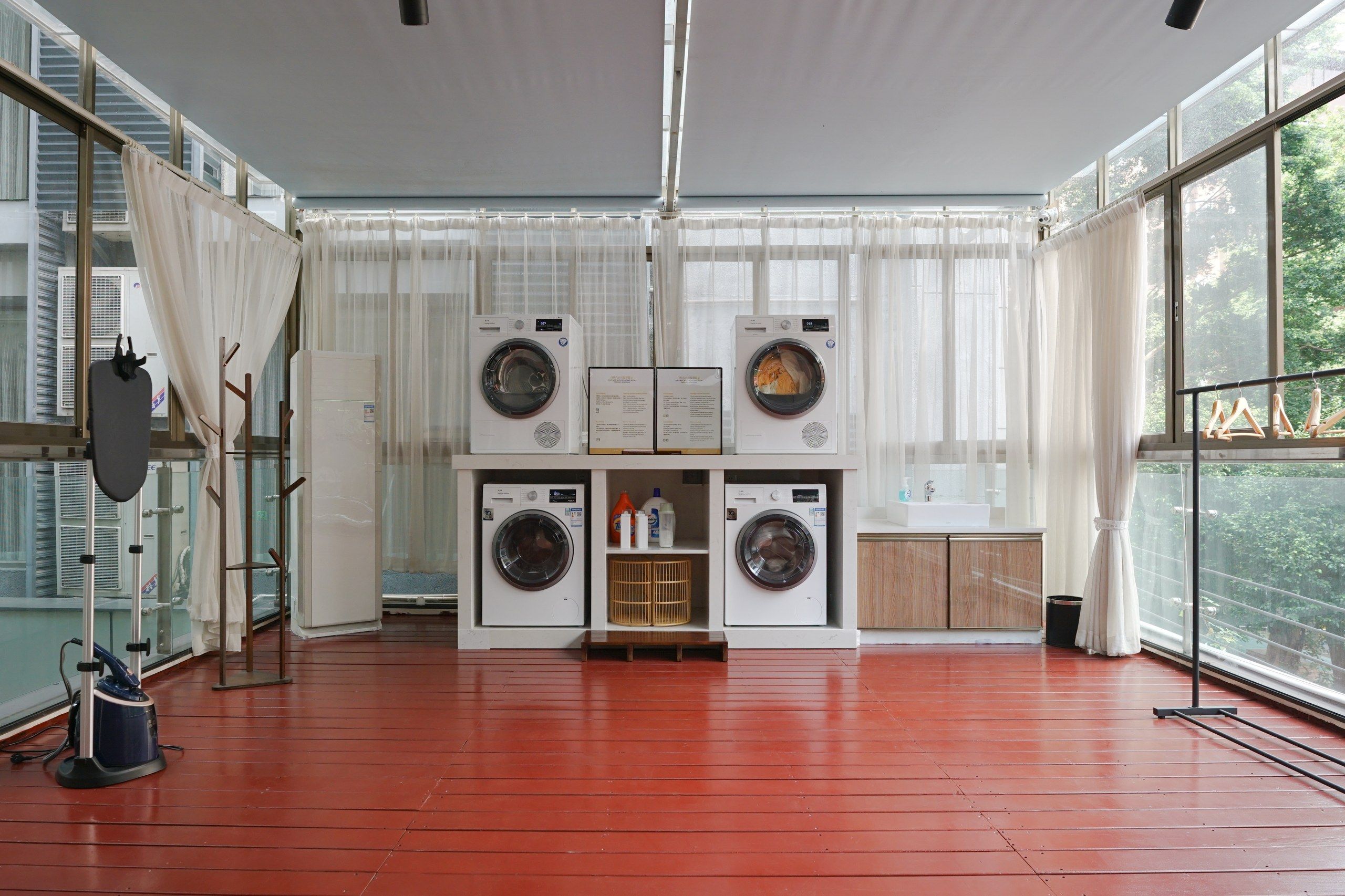 A laundry room with four washing machines, a vacuum cleaner, and a wooden cabinet.