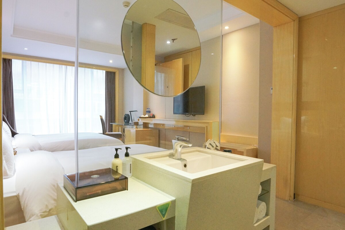 A hotel room with a bed, a bathroom with a sink and mirror, and a television.