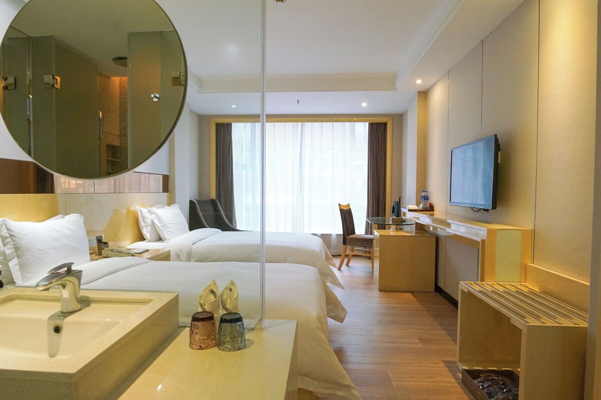 A hotel room with a large bed, a desk, a TV, and a bathroom.