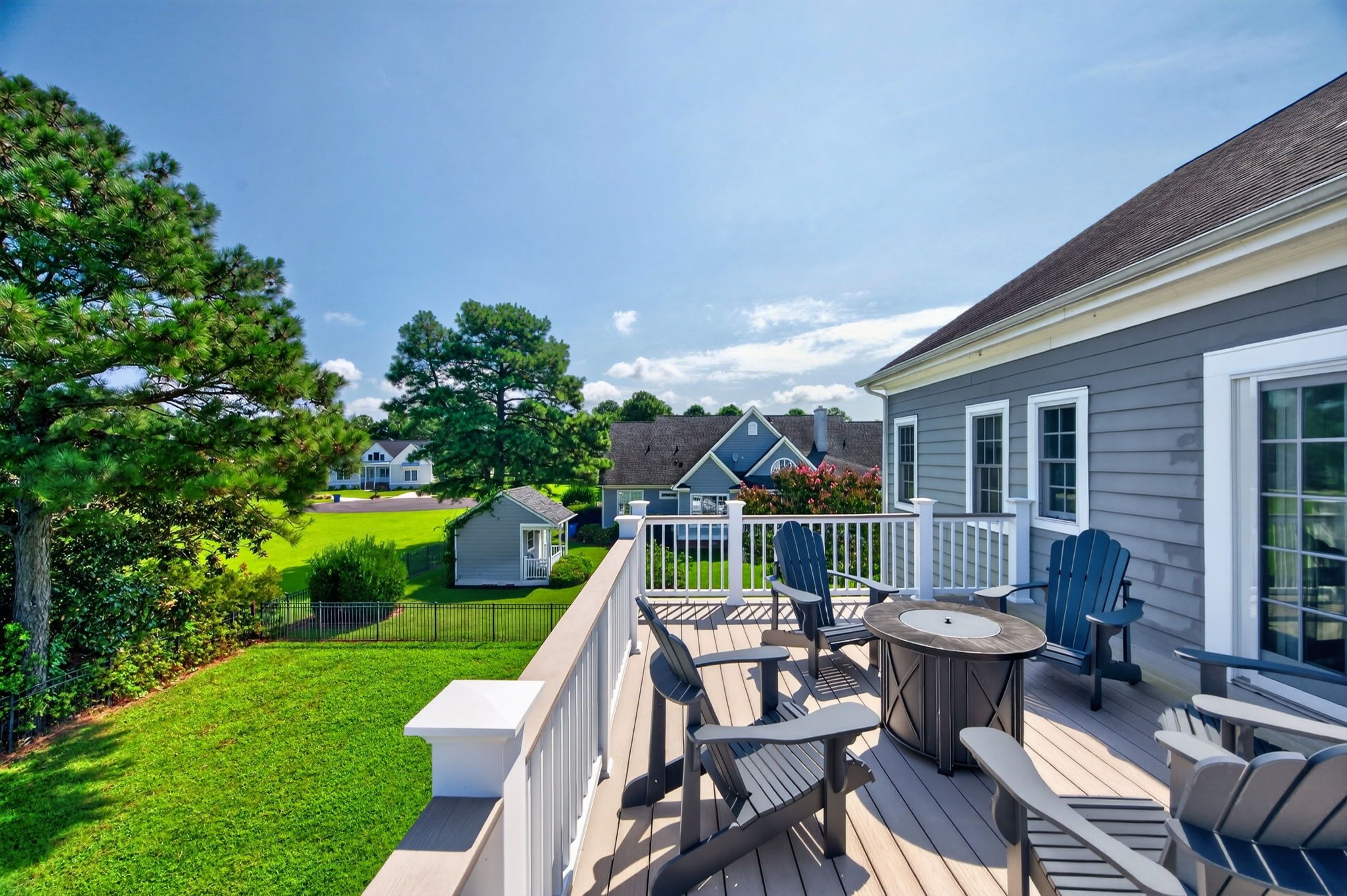 A deck with outdoor furniture, a lawn, and a house in the background.