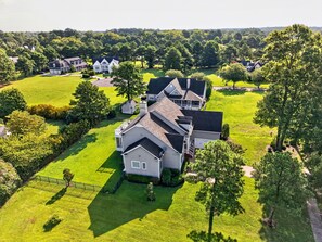 Une grande maison à plusieurs étages, dotée d’une pelouse bien entretenue et entourée d’arbres.