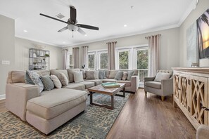 A living room with a sectional sofa, a coffee table, a side table, and a cabinet. - The Coastal Drift Communal Pool (Miramar Beach)